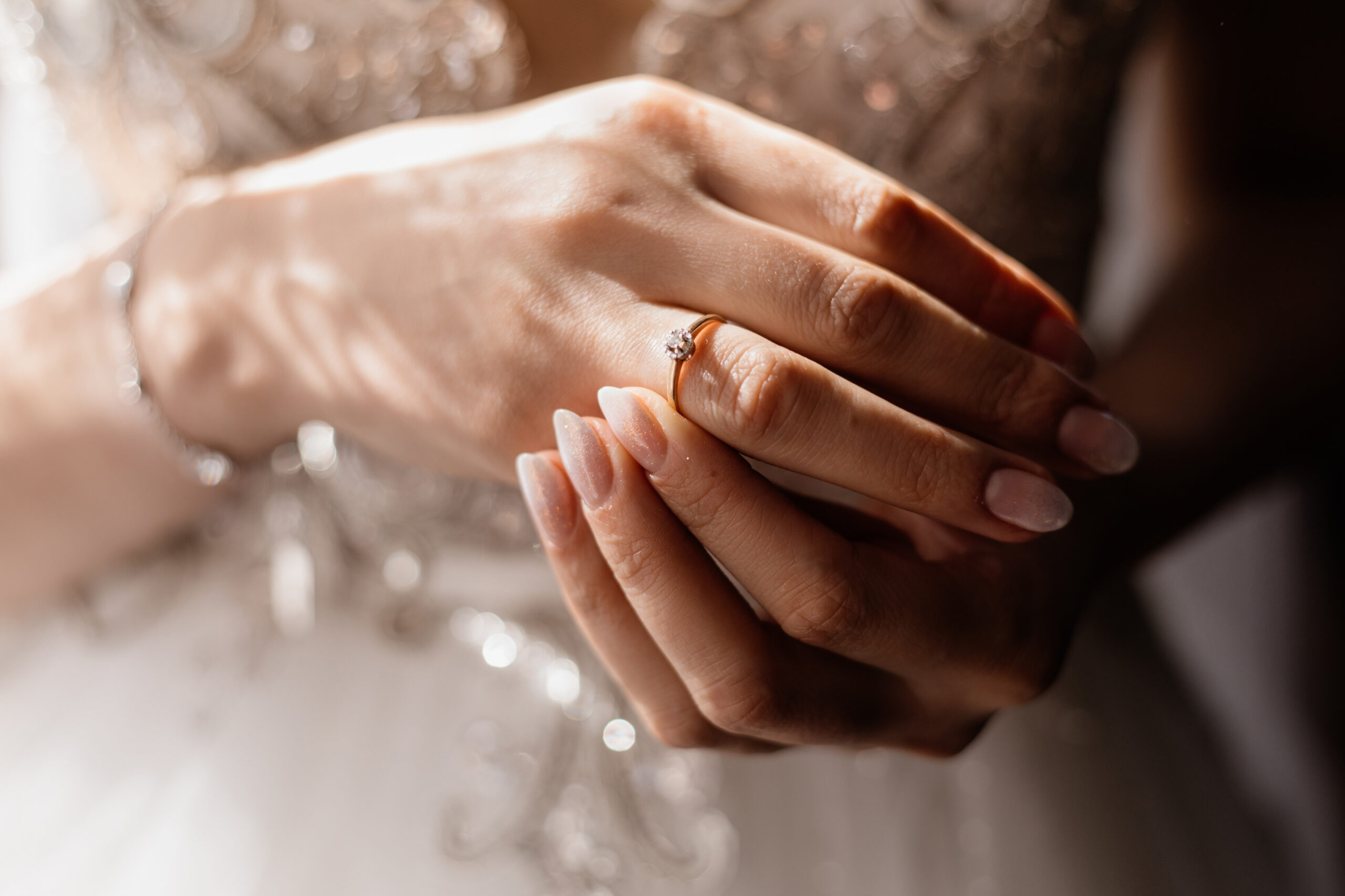 Bride hands close up, with beautiful manicure and minimalistic engagement ring